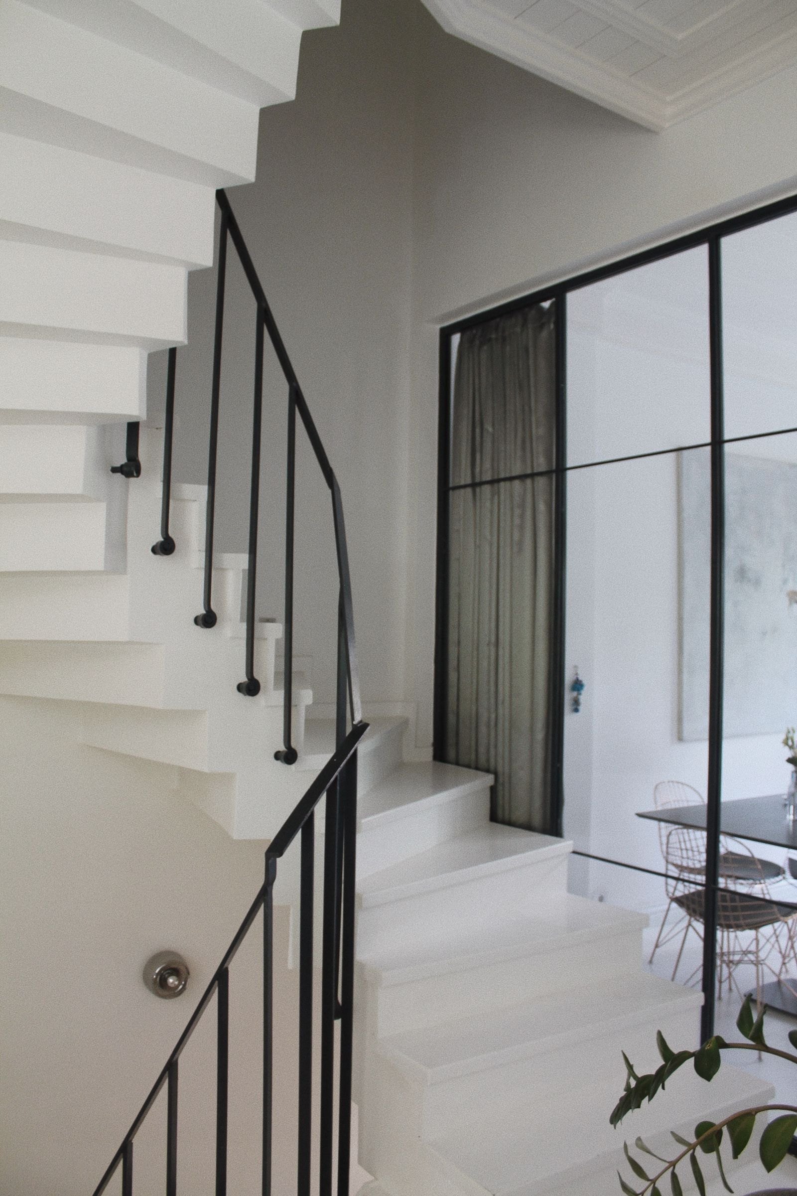 A quiet white stairwell with a black railing and soft grey light