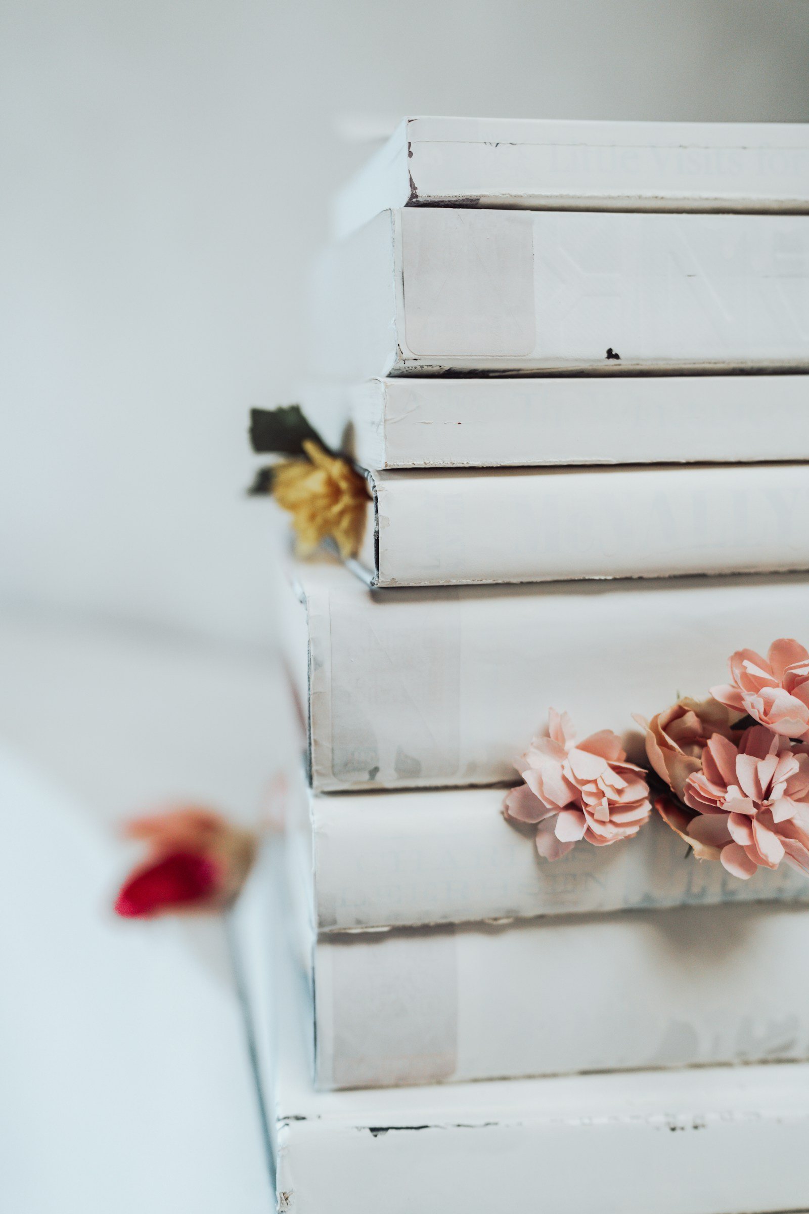 A stack of white books with dusty-pink flowers tucked between them