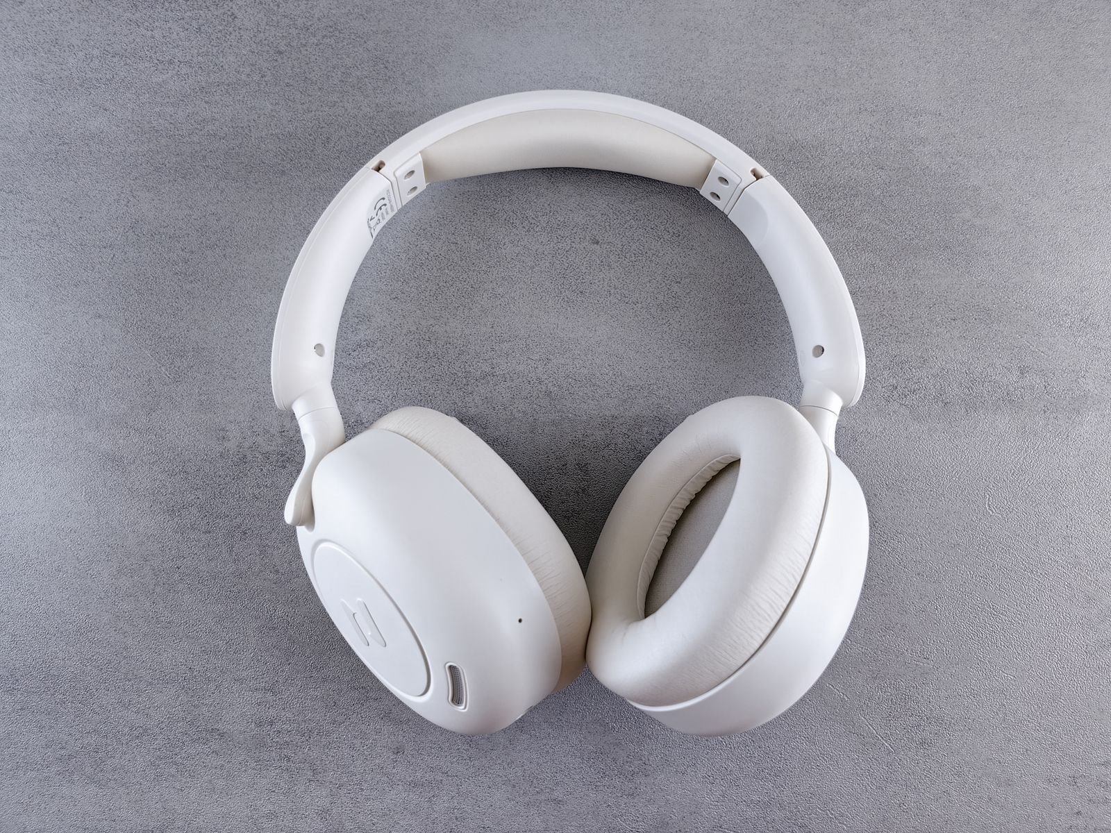 Soft white headphones resting on a pale grey surface